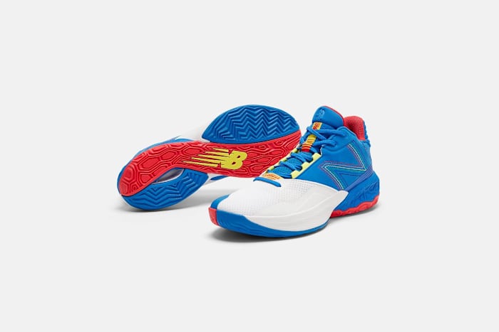 Side view of white, blue, and red New Balance basketball shoes.
